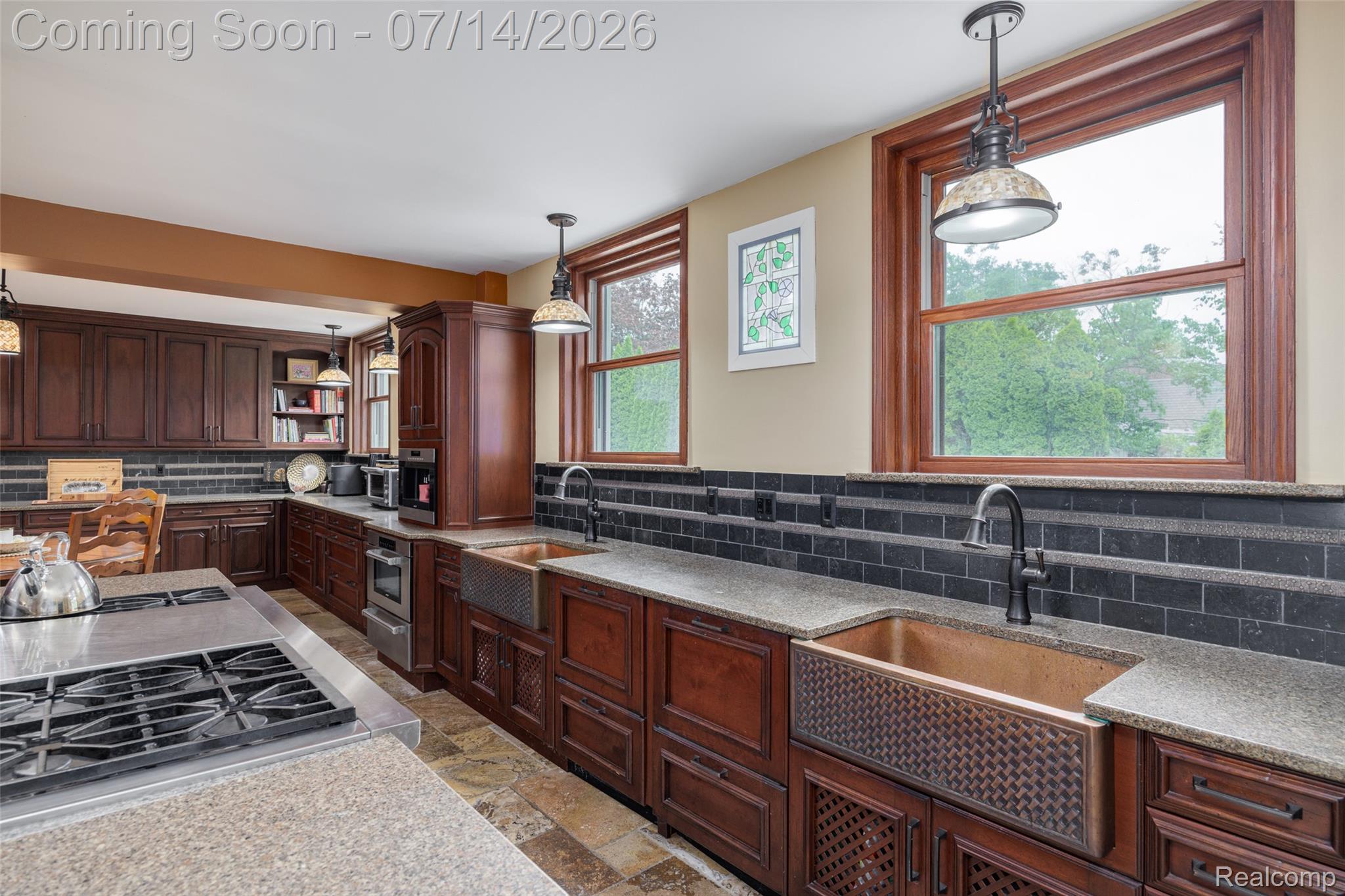 189 Cloverly Road Grosse Pointe, MI 48236 - Photo 24 of 96 Kitchen featuring rich wood cabinetry, stone countertops, a subway tile backsplash, two farmhouse-style copper sinks, and a built-in range on the island