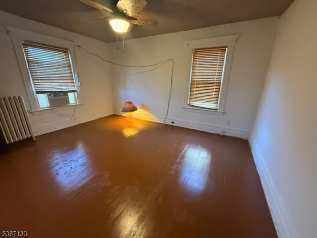 a view of an empty room with window and wooden floor