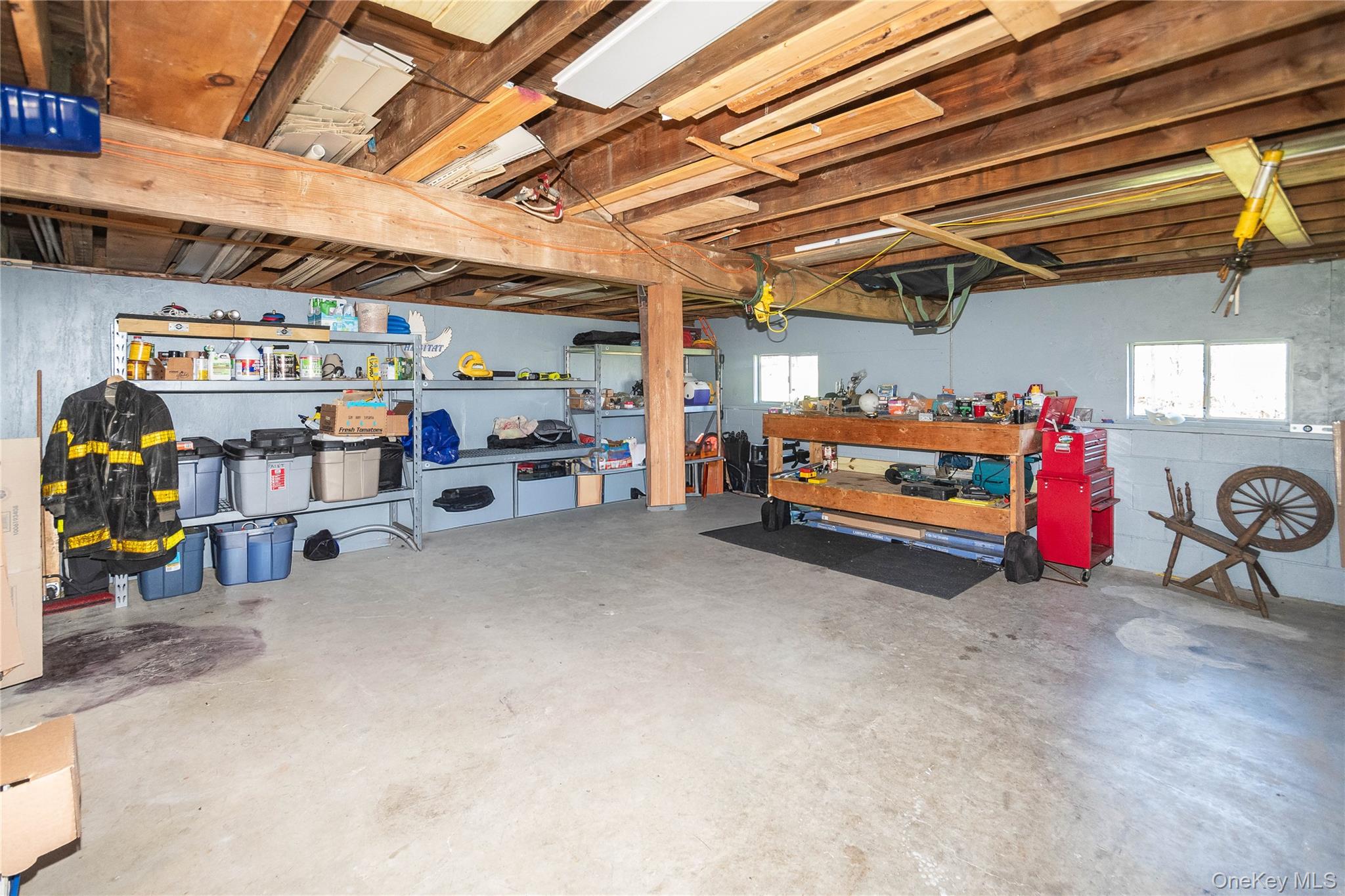 3 Duby Road Wallkill, NY 12589 - Photo 38 of 40 Spacious utility area featuring exposed wood beam ceiling, concrete flooring, built-in shelving, two windows, and a workbench