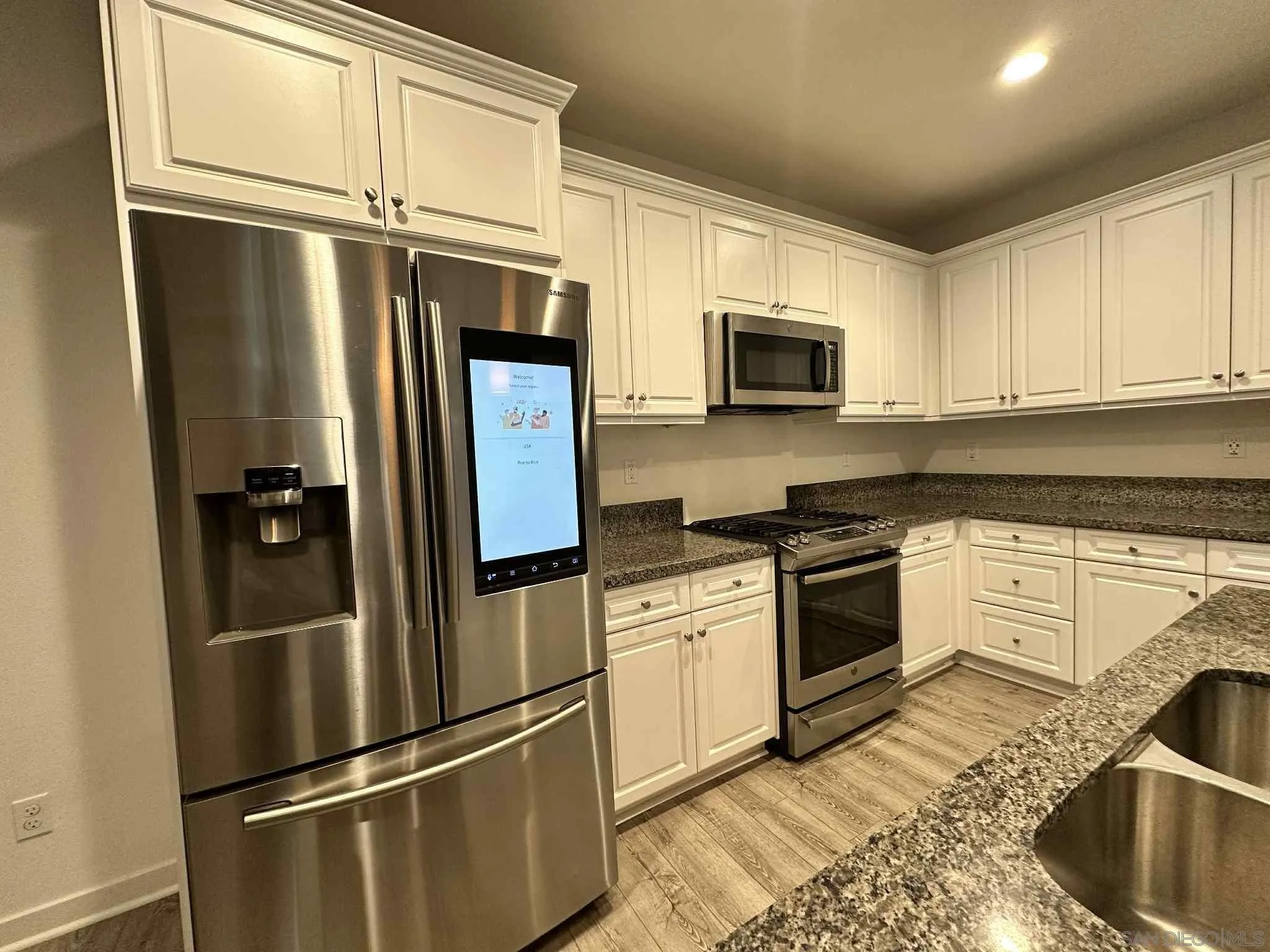 1958 P.º Lugo Chula Vista, CA 91913 - Photo 50 of 68 a kitchen with stainless steel appliances granite countertop a refrigerator a stove a sink and white cabinets with wooden floor
