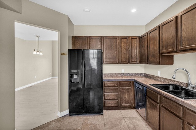 14108 Pepi Band Road Draper, UT 84020 - Photo 13 of 36 Kitchen featuring wood cabinetry, stone-look countertops, a black side-by-side refrigerator, a black double-basin sink with a chrome faucet, and tile flooring