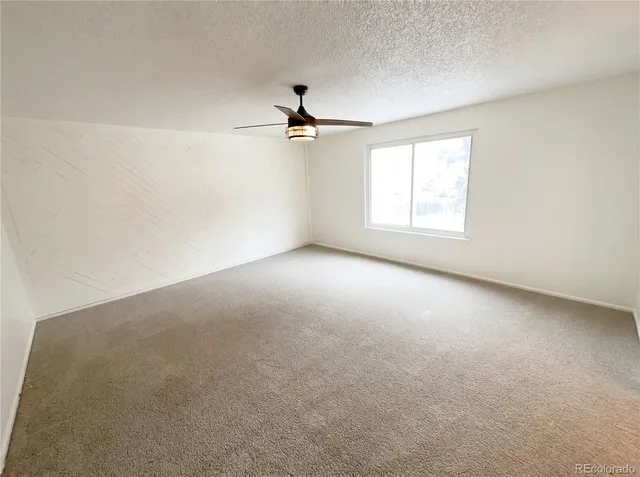 an empty room with a window and a ceiling fan