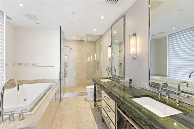 a bathroom with a granite countertop double vanity sink a mirror and a bathtub