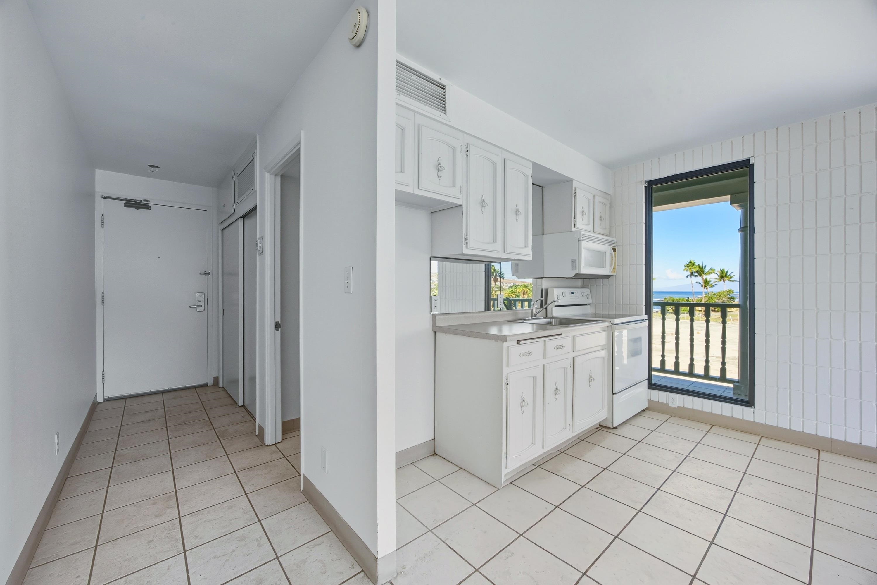a kitchen with white cabinets and window