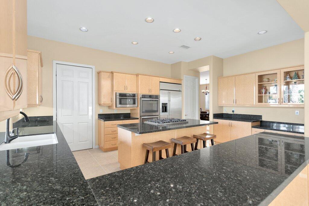 8 MacBeth Court Rancho Mirage, CA 92270 - Photo 11 of 46 a large white kitchen with kitchen island a stove a sink a refrigerator and windows