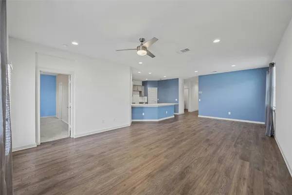 a view of empty room with wooden floor and ceiling fan