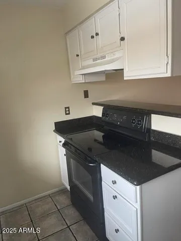 a kitchen with granite countertop white cabinets and black appliances