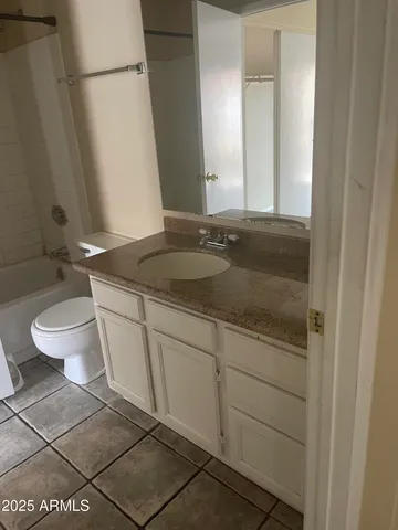 a bathroom with a granite countertop sink a toilet and a mirror