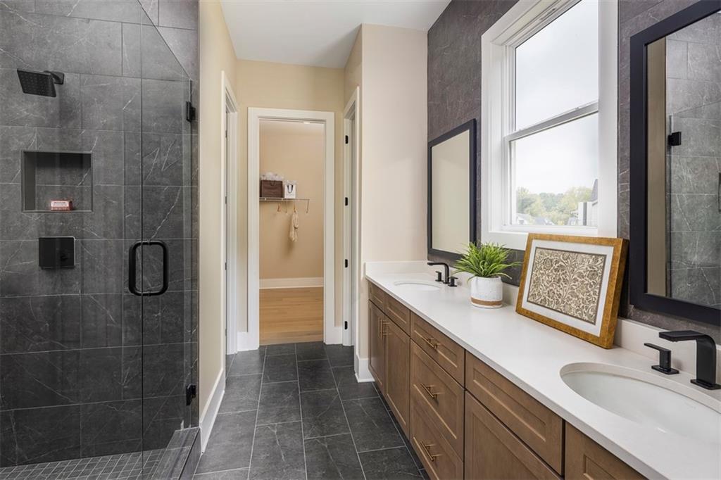 214 Mooney Road Woodstock, GA 30188 - Photo 12 of 17 a bathroom with a double vanity sink a large mirror a shower and a bathtub