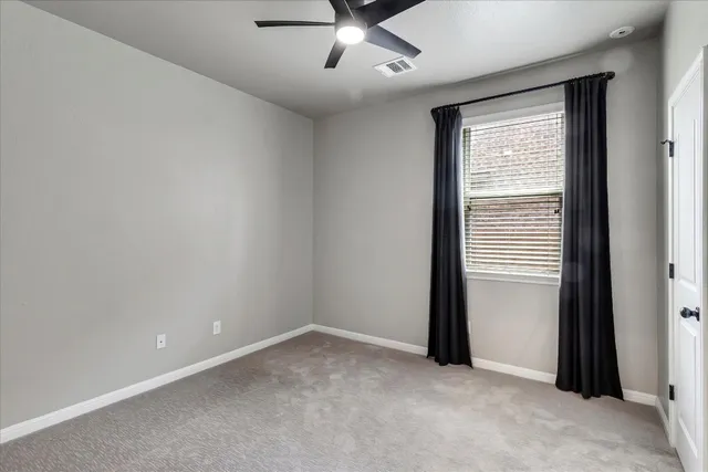 an empty room with a ceiling fan and window