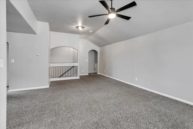 an empty room with chandelier fan and windows