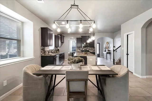 a dining room with wooden floor a chandelier a wooden table and chairs