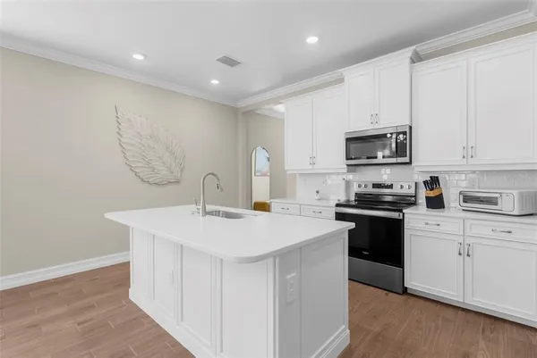 a kitchen with stainless steel appliances a sink stove and white cabinets