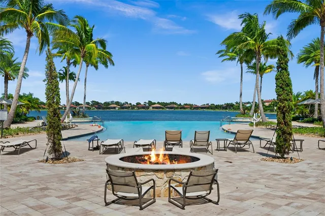 a view of a lake with table and chairs potted plants and palm trees