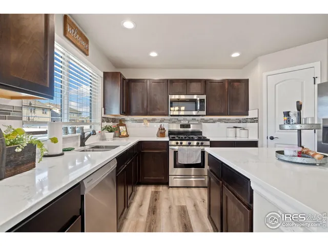 a kitchen with kitchen island granite countertop a sink wooden cabinets and stainless steel appliances