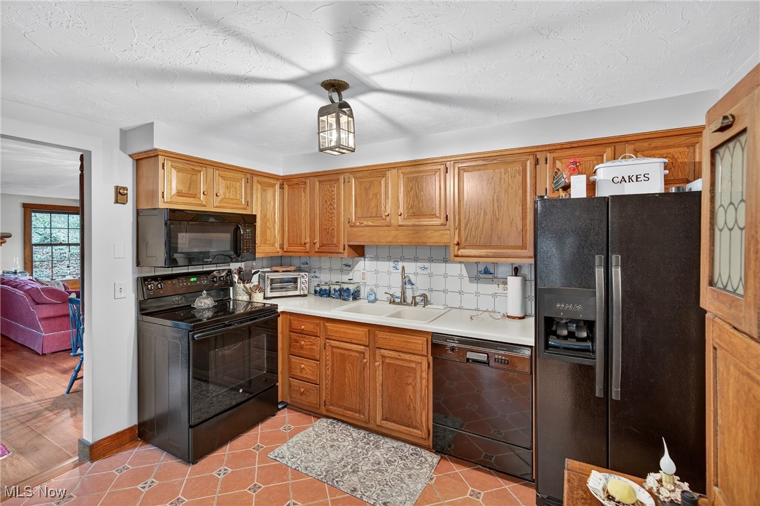 25700 Winona Road Homeworth, OH 44634 - Photo 9 of 49 Kitchen with tasteful backsplash, black appliances, light countertops, a textured ceiling, and light tile patterned floors