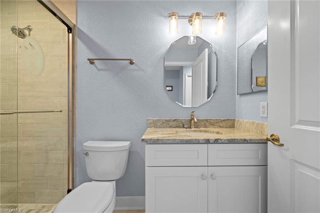 19081 Ridgepoint Drive, Unit 102 Estero, FL 33928 - Photo 9 of 50 a bathroom with a granite countertop sink a toilet and mirror
