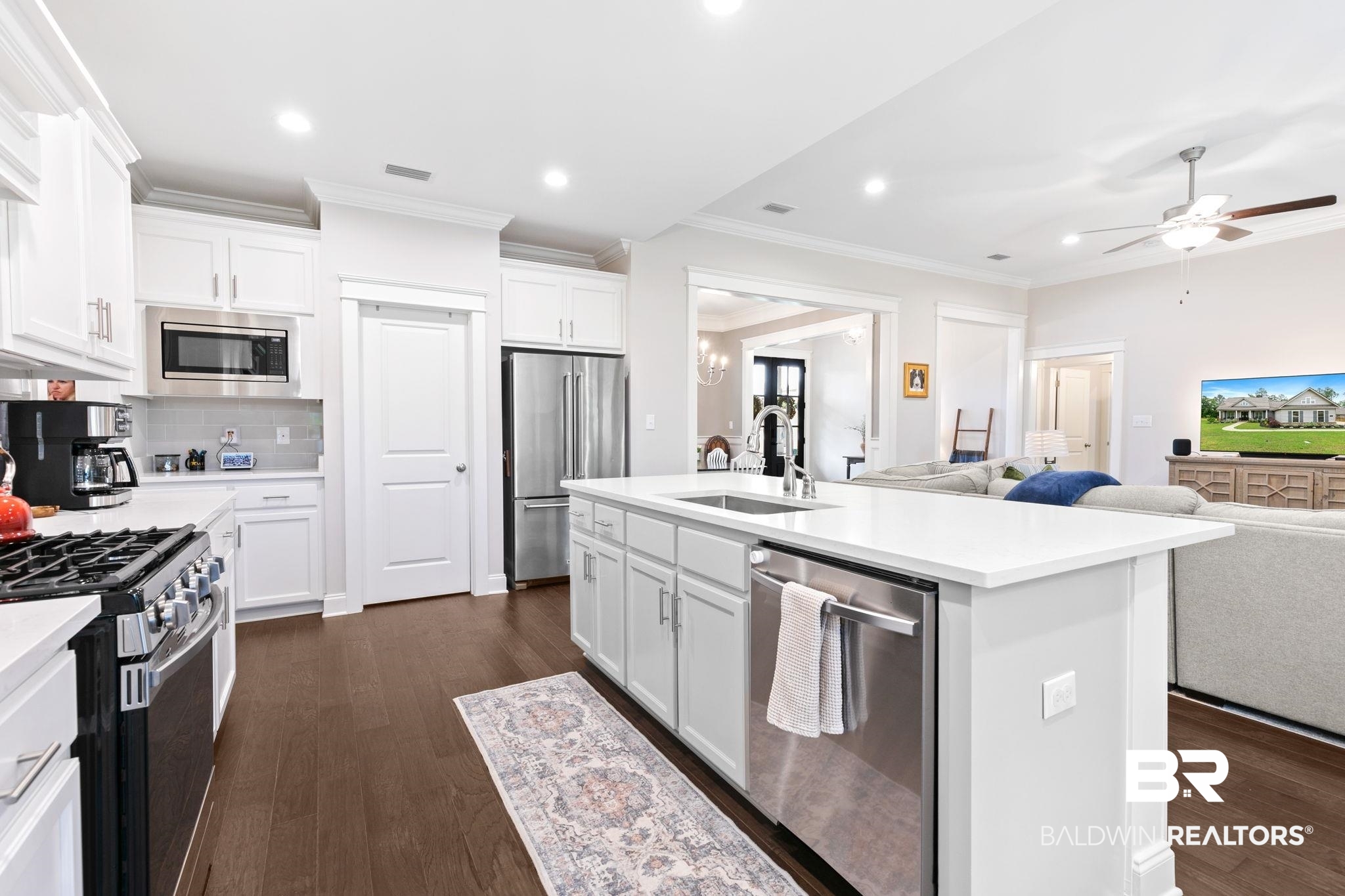 13233 Ibis Boulevard Daphne, AL 36527 - Photo 14 of 100 White kitchen featuring a gas range, stainless steel appliances, and a central island with an integrated sink and dishwasher