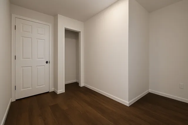 a view of an empty room with wooden floor and closet
