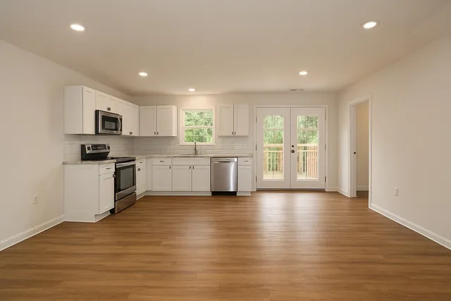 a kitchen with a white cabinets and wooden floor