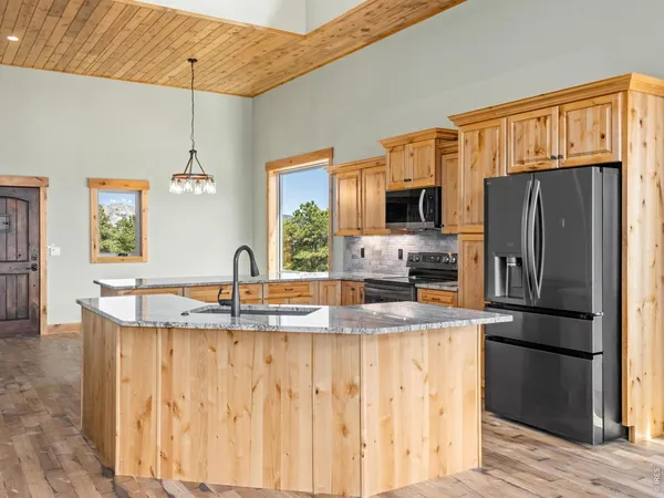 a kitchen with granite countertop a refrigerator a stove a sink a window and wooden floor
