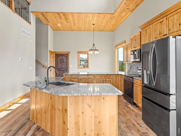 a kitchen with stainless steel appliances granite countertop a sink refrigerator and cabinets