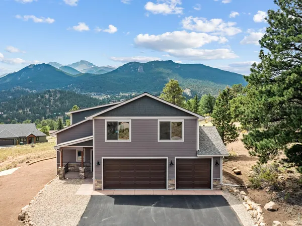 a front view of a house with a yard and mountain view in back
