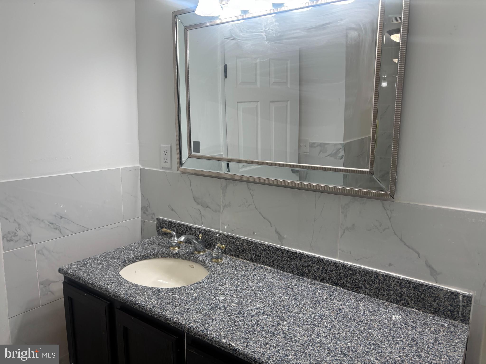1623 West Lexington Street Baltimore, MD 21223 - Photo 15 of 26 a bathroom with a granite countertop sink and a mirror