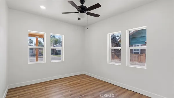 a view of an empty room with a window and wooden floor