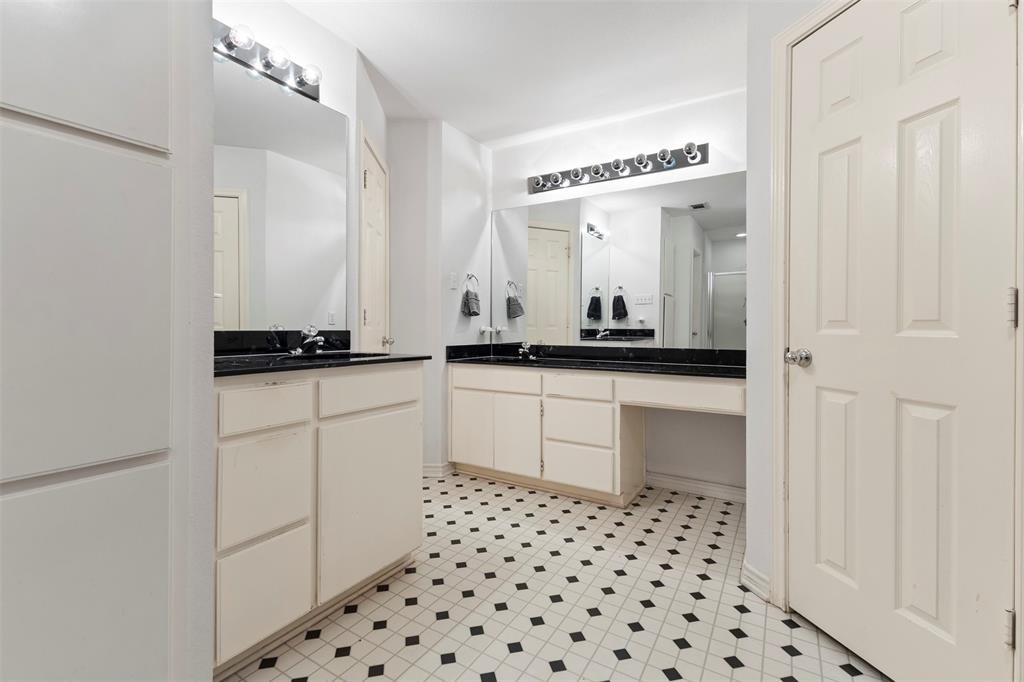 401 Rugged Drive Red Oak, TX 75154 - Photo 22 of 40 Bathroom featuring a black and white geometric tile floor, two separate vanity cabinets with sinks, dark countertops, and wall-mounted light fixtures