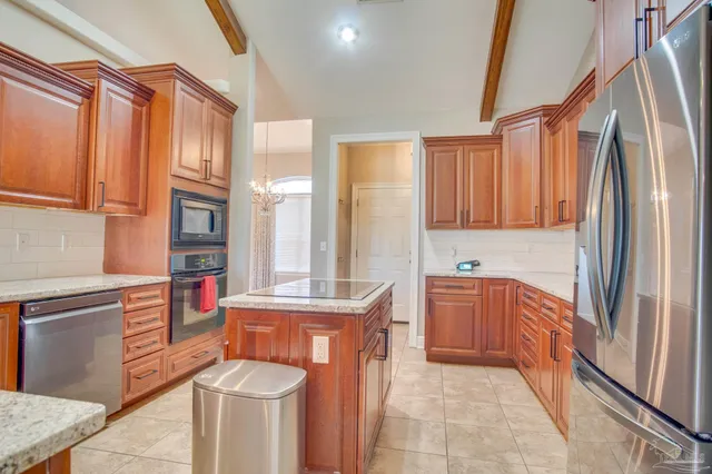 a kitchen with stainless steel appliances granite countertop a refrigerator a stove and a sink with wooden cabinets