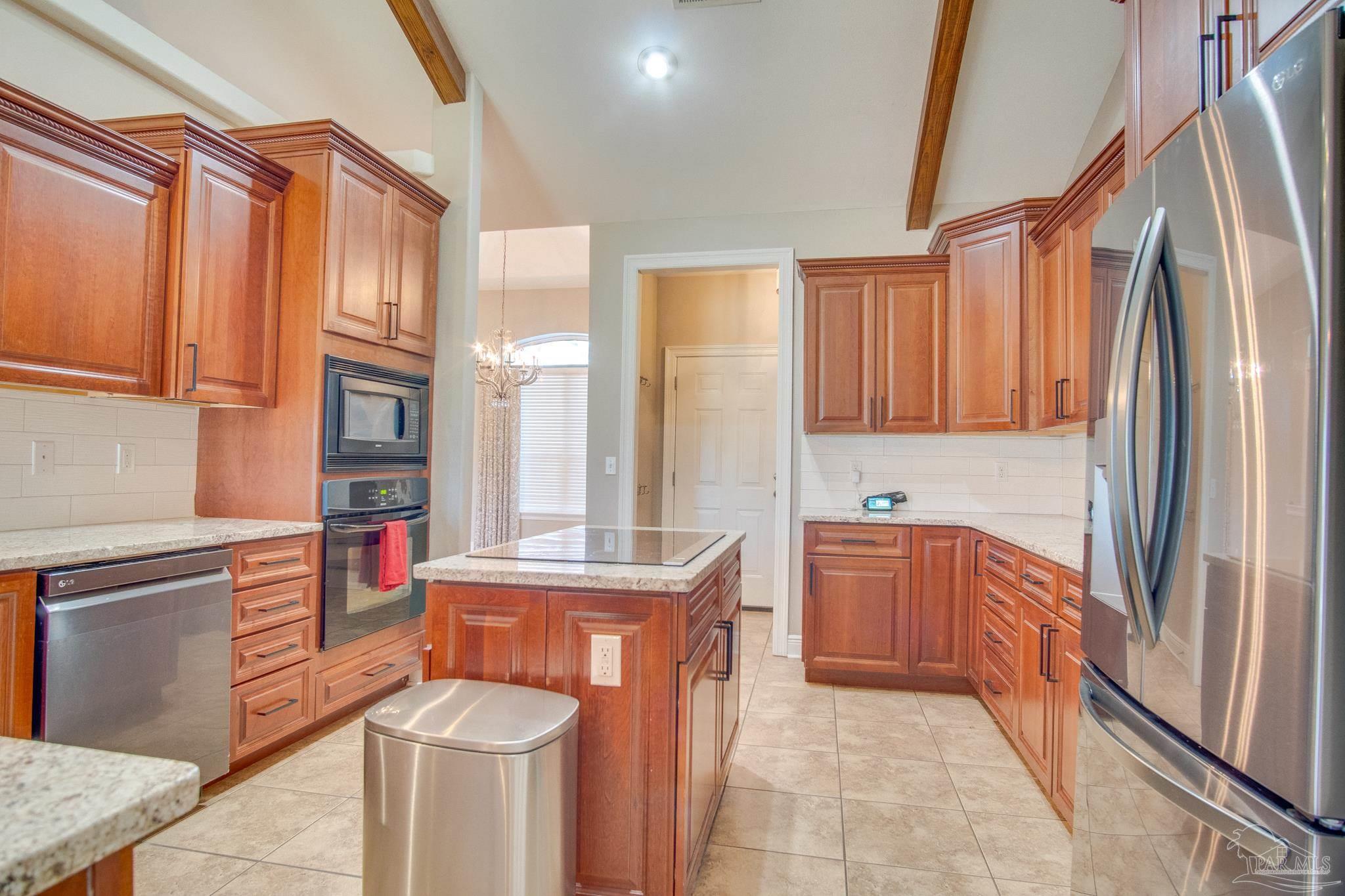 2655 Masters Boulevard Navarre, FL 32566 - Photo 13 of 43 a kitchen with stainless steel appliances granite countertop a refrigerator a stove and a sink with wooden cabinets