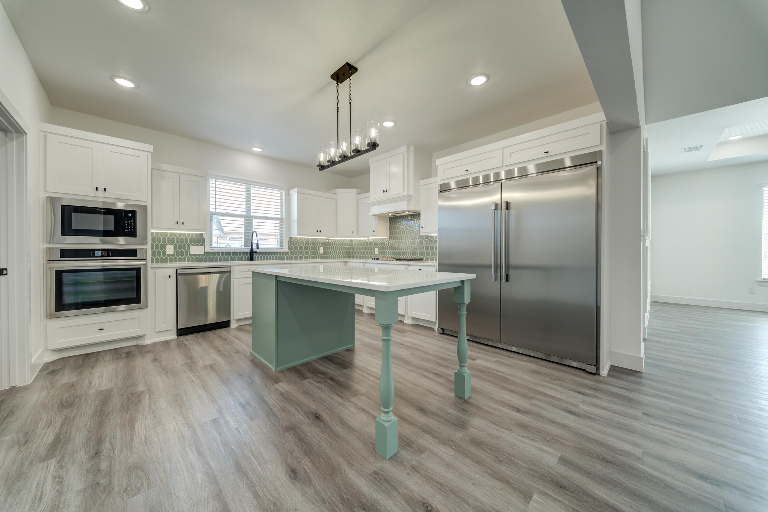 7522 56th Street Lubbock, TX 79407 - Photo 21 of 47 a kitchen with stainless steel appliances kitchen island granite countertop a refrigerator a stove a microwave oven a sink with island and chairs with wooden floor