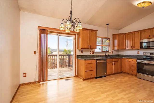 a kitchen with stainless steel appliances granite countertop a stove a sink and a refrigerator with wooden floor