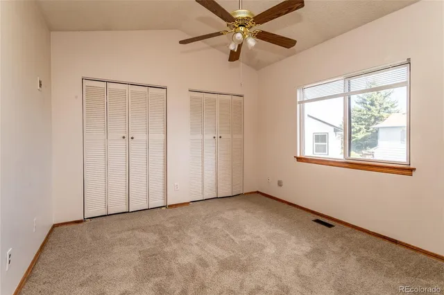 an empty room with windows and fan