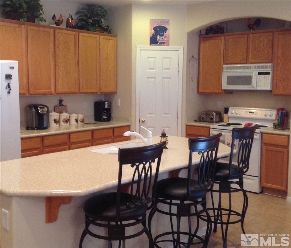 1413 Gaucho Lane Reno, NV 89521 - Photo 3 of 24 a kitchen with stainless steel appliances a table chairs and a refrigerator