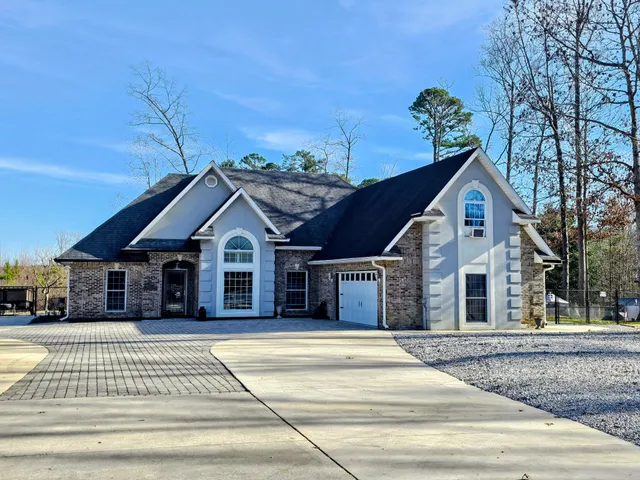 a front view of a house with a garden and trees