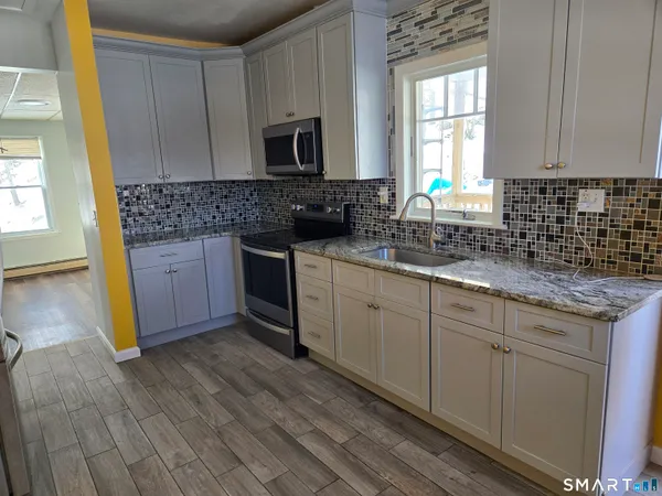a kitchen with stainless steel appliances granite countertop a stove a sink and a microwave