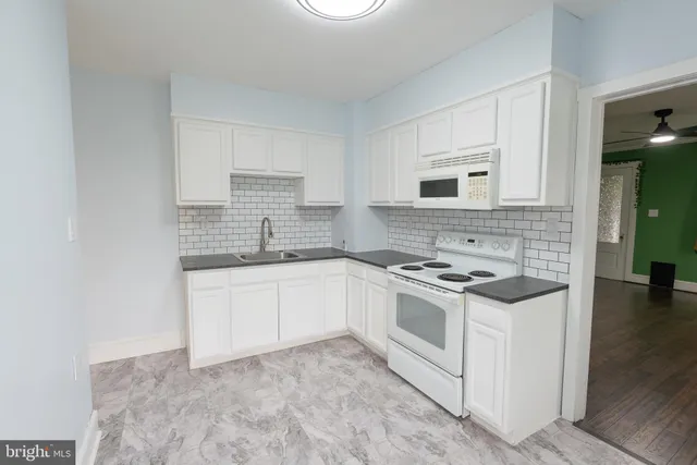 a kitchen with stainless steel appliances granite countertop a sink a stove a refrigerator with grey cabinets