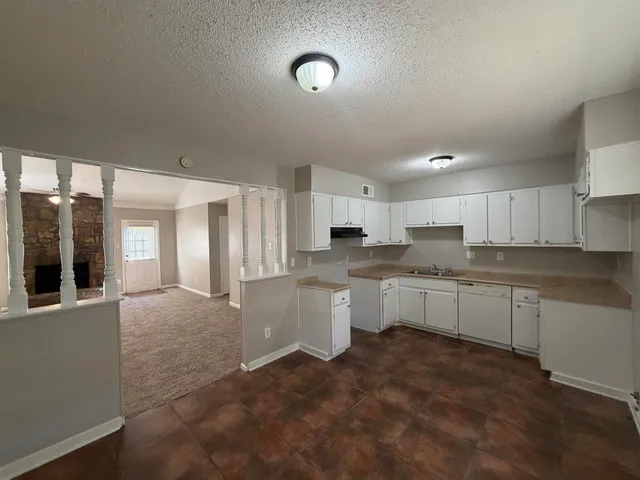 a large white kitchen with a sink and dishwasher a stove top oven with wooden floor