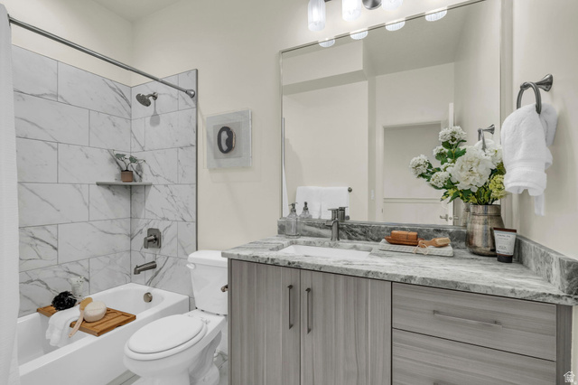 4016 South Burch Way Ogden, UT 84405 - Photo 12 of 30 Full bathroom featuring a white tub with marble-look tile surround, a built-in corner shelf, and brushed nickel fixtures