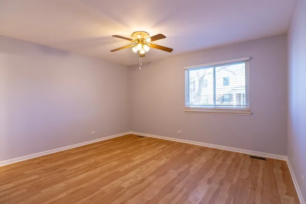wooden floor in an empty room with a chandelier fan