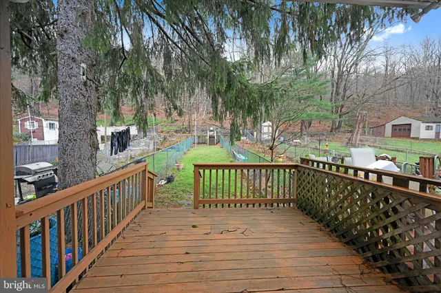 a view of a deck with large trees and wooden fence