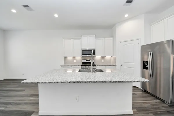 a kitchen with stainless steel appliances granite countertop a sink refrigerator stove and microwave