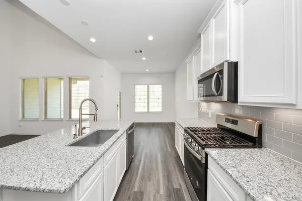 a kitchen with stainless steel appliances granite countertop a sink stove and cabinets