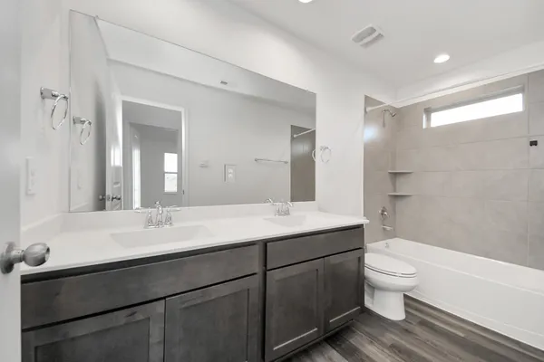 a bathroom with a double vanity sink toilet mirror and shower