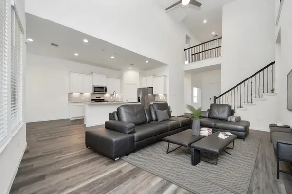 a living room with furniture and kitchen view with wooden floor
