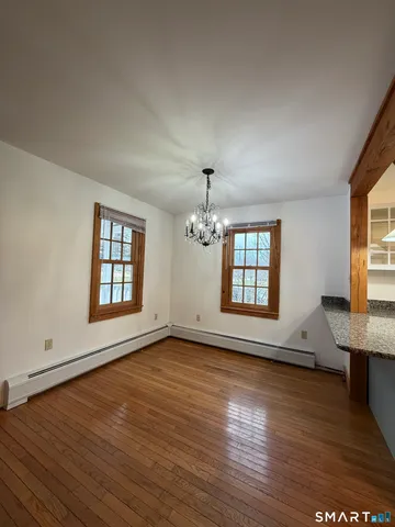 an empty room with wooden floor chandelier and windows