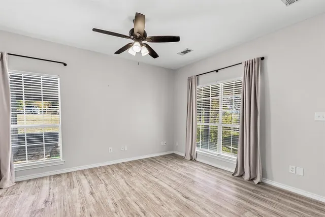 a view of empty room with wooden floor and fan