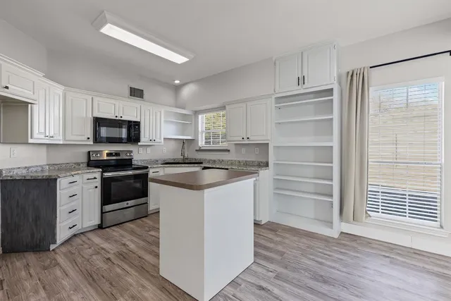 a kitchen with granite countertop a refrigerator stove and wooden floor